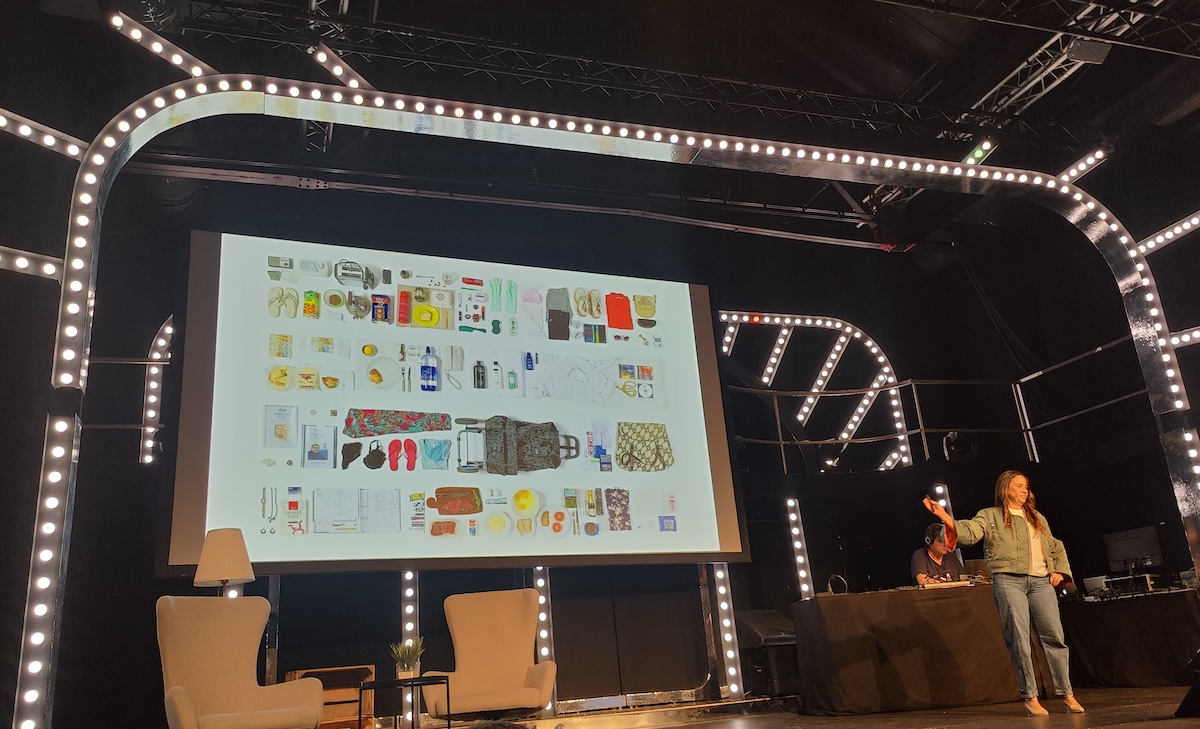 Paula Zuccottia on stage with a slide showing her mothers possession laid out on white canvas as a piece of artwork