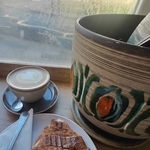 Croissant and latte next to a plant pot in a coffee shop