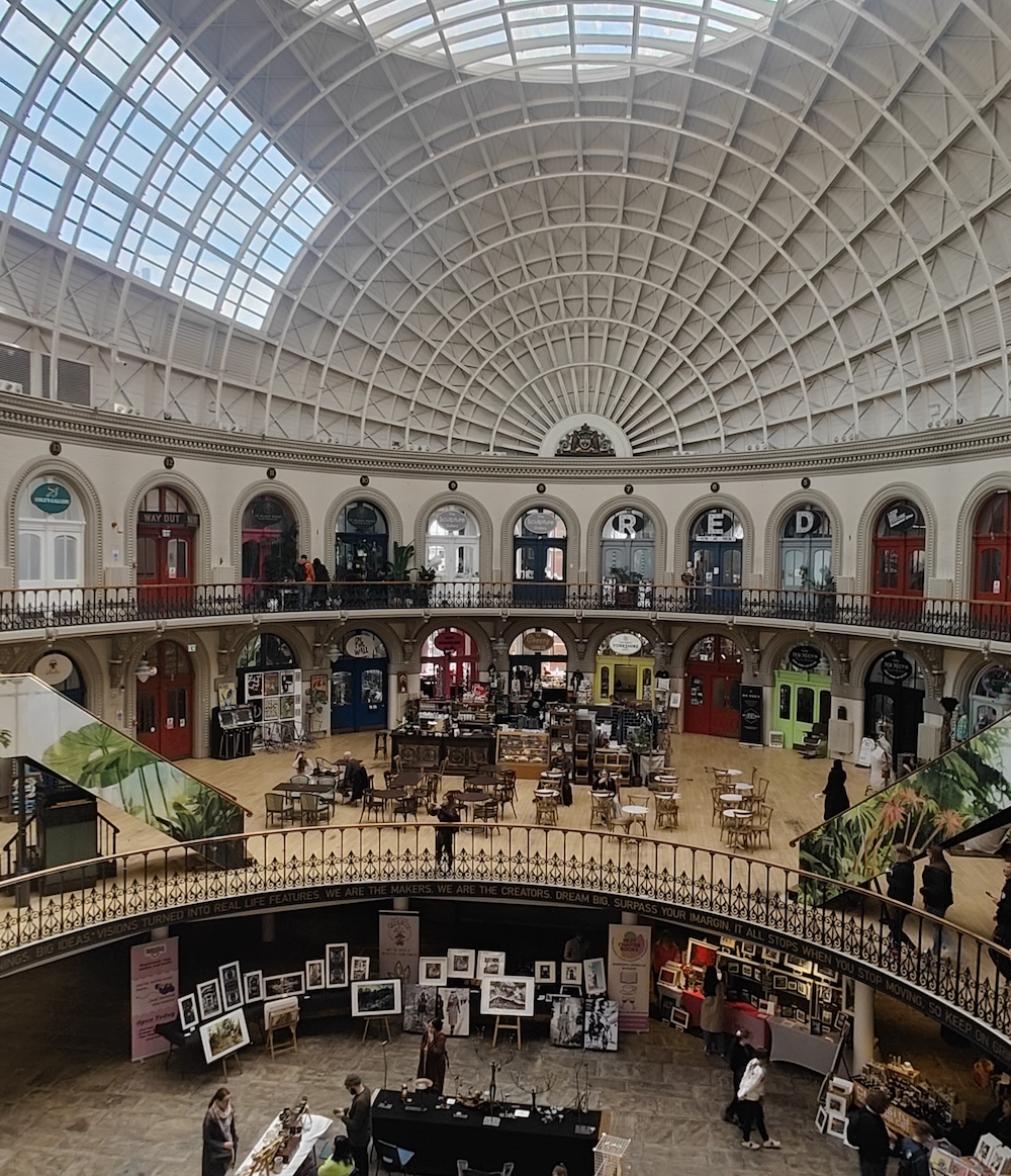 Inside Leeds Corn Exchange, a circle of small shops surround a balcony and elegant staircase