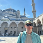 Calum in a green shirt and sunglasses with the backdrop of Blue Mosque, Istanbul