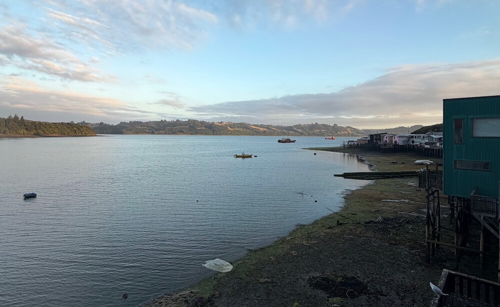 Waterside view of Castro with fishing boats, Palafitos and tide out
