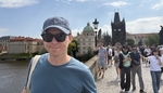 Calum in shades on the Charles Bridge busy with other tourists in Prague on a clear sunny day