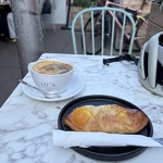 A large white cup of coffee and apricot pastry on a stylish black plate