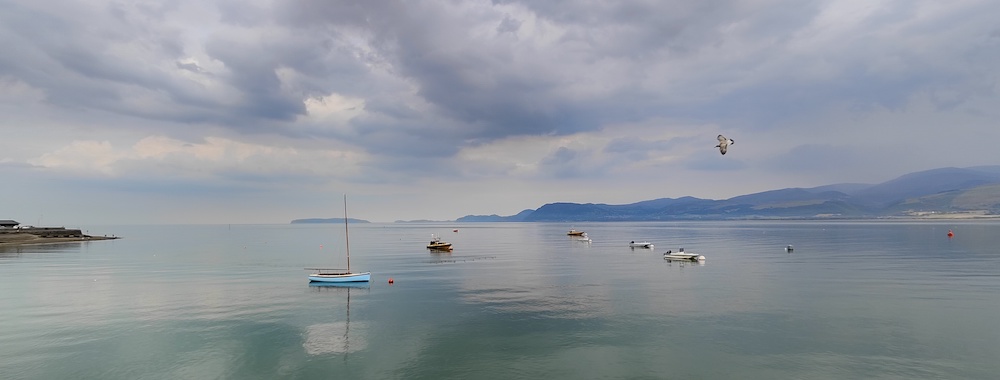 Calm waters with stationery trawlers and backdrop of moutains