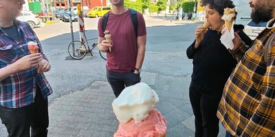 Holding a cone of ice cream with vanilla and rhubarb. Backdrop of other btconf attendees