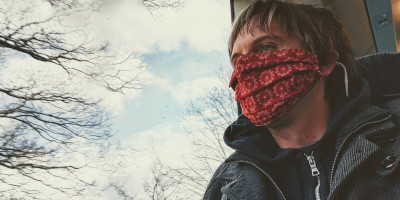 Calum on a train wearing London Eye decorated red face mask