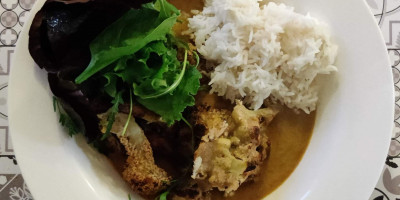 Katsu curry with cauliflower, greens and white rice in a white bowl