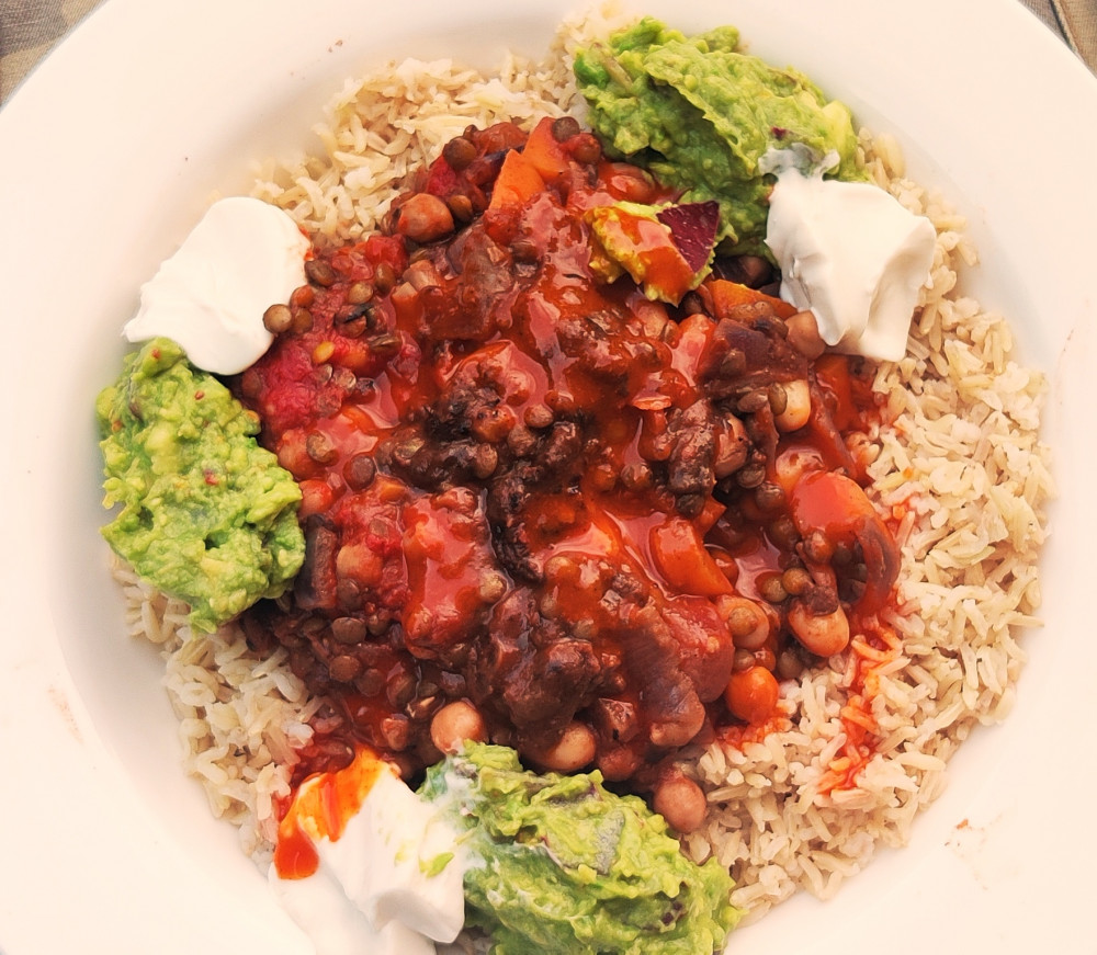 Vegan chili dish surrounded with brown rice