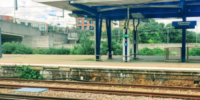 Ashford International station with green foliage growing alongside the platform edge