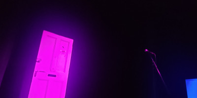 Soho theatre stage with door and fridge under purple lighting