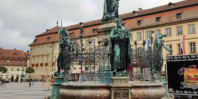 Market square view with statue in the centre and red flowers in foreground