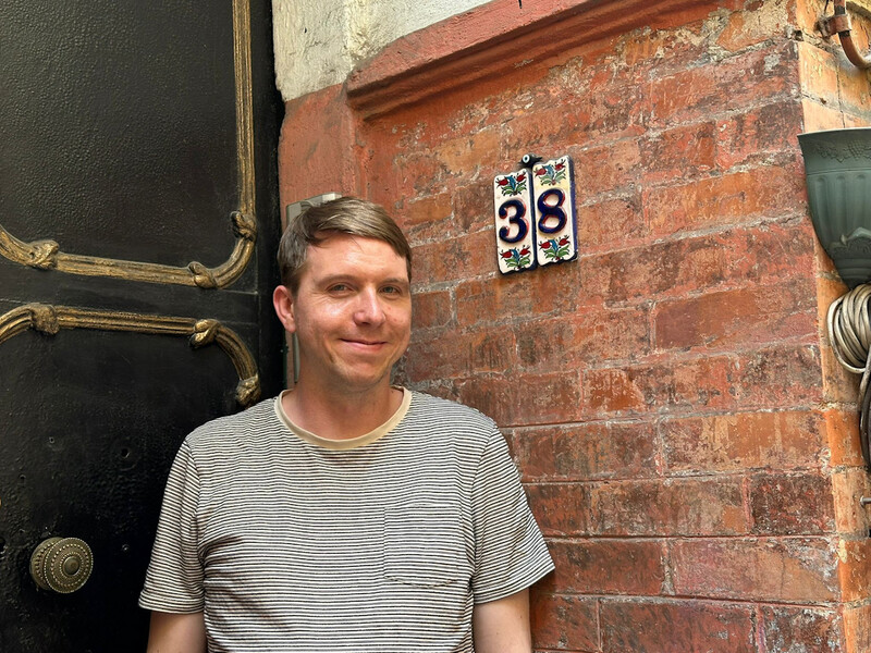 The house number 38 on ceramic tiles with a pretty backdrop of a black door, Calum stand beside