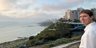 Coast side view with high-rise apartments, walkway bridge and Calum looking towards camera