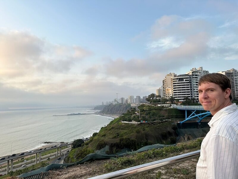 Coast side view with high-rise apartments, walkway bridge and Calum looking towards camera