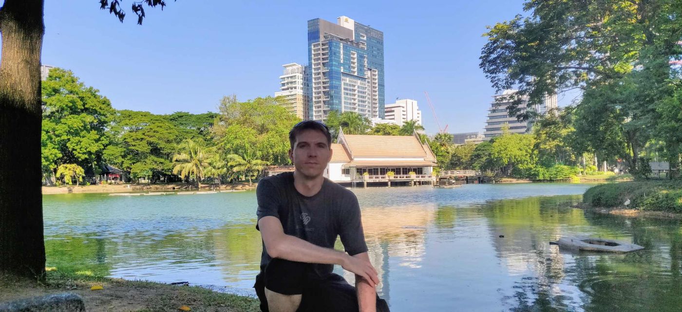Calum perching by a lake in Lumphini Park